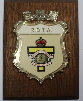 R.O.T.A plastic and enamel badge mounted on wood base.