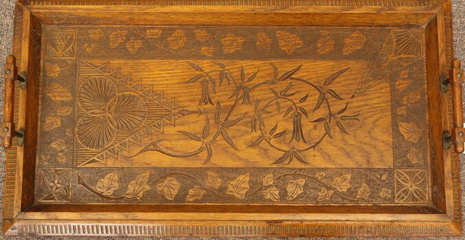 A hand crafted wooden serving tray with carved leaf pattern.