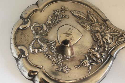 Silver hand mirror back  showing embossed design and letter M