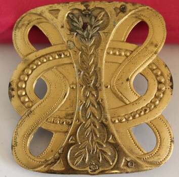 Gold metallic belt buckle with embossed leaf design