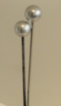 A pair of hat pins with faux silver heads.