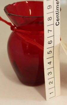 Small ruby glass vase with scale in centimetres