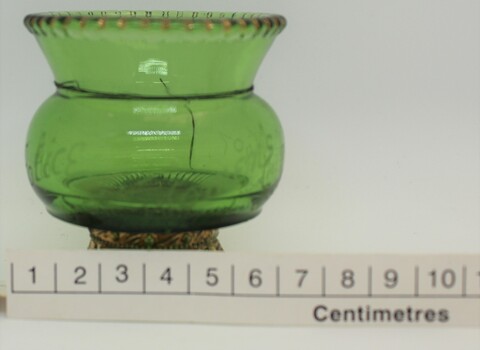 Small green glass vase with scale in centimetres.