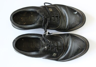 A pair of black leather golf shoes.