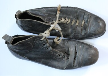 Black leather football boots tied together with laces.