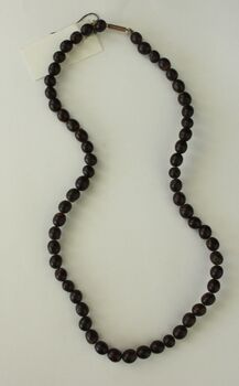 A short necklace of uniform sized beads or possibly seeds.