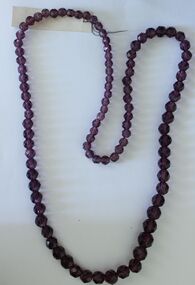 A long string of mauve faceted beads of varied size.