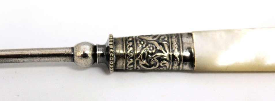 Decorative silver work on shaft between the handle and fork blade