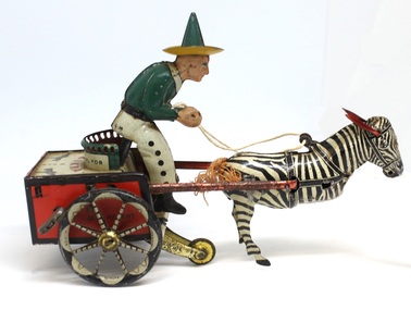 Side view of a windup toy cart being pulled by a zebra