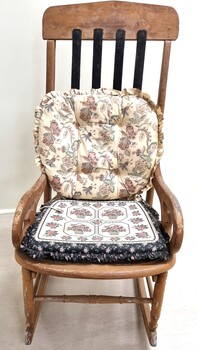 An old rocking chair with 2 cushions attached