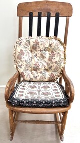 An old rocking chair with 2 cushions attached