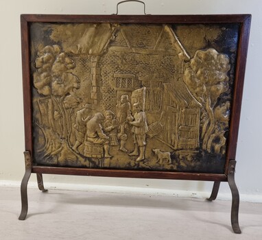 Beaten copper free standing fire screen with scene of people and building