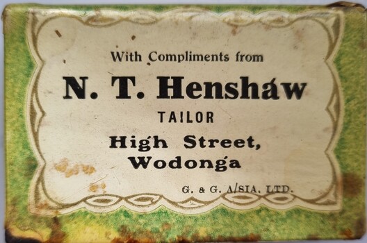 Green and white metal match box holder with Henshaw's business promotion