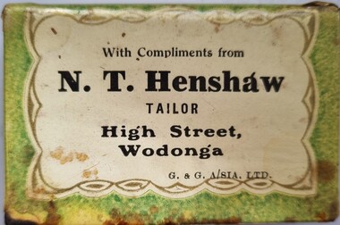 Green and white metal match box holder with Henshaw's business promotion