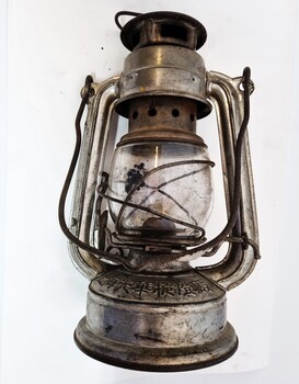 Small kerosene lantern showing Chinese characters imprinted on one side.