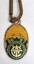 Small oval badge plated in green and gold enamel with gold logo