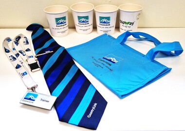 A collection of CountryLink items and uniform including a tie, lanyard and badge, cups and a bag.