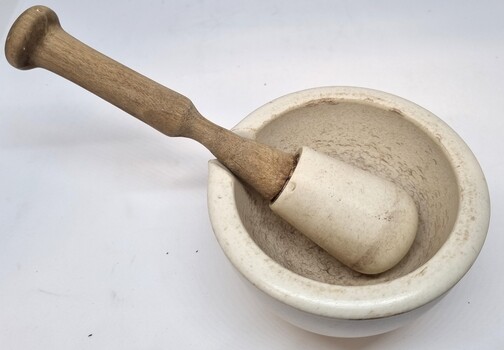 Smaller mortar and pestle with indentation on edge to rest mortar.