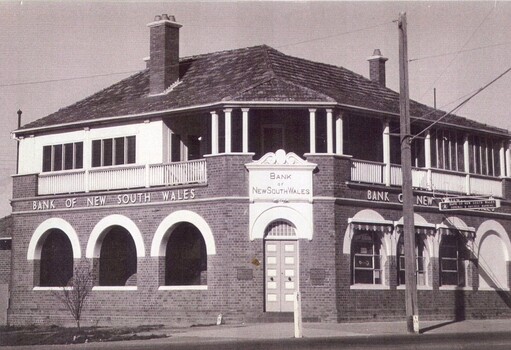 Brick building with white window casements and balcony upstairs