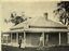 3 gentleman standing on the verandah in front of a brick building