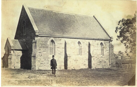 Early photo of St Luke's Church with man in foreground wearing black long coated suit and top hat.