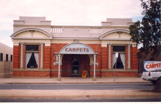 A brown and cream brick building with advertising canopy over door way