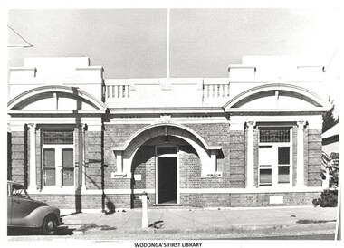 A brick building with large windows either side of the central door. A fire hydrant at the front.