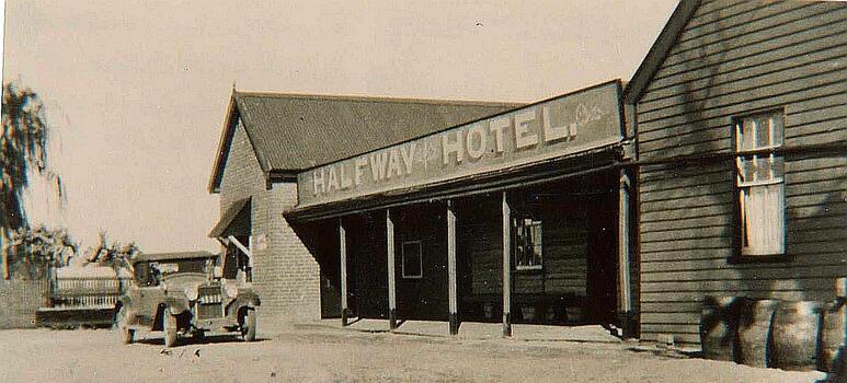 A brick hotel building with a car parked at the front.