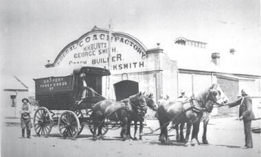 A coach pulled by 4 horses in front of the Federal Coach Factory. 4 men including 2 Indian hawkers are in the foreground.
