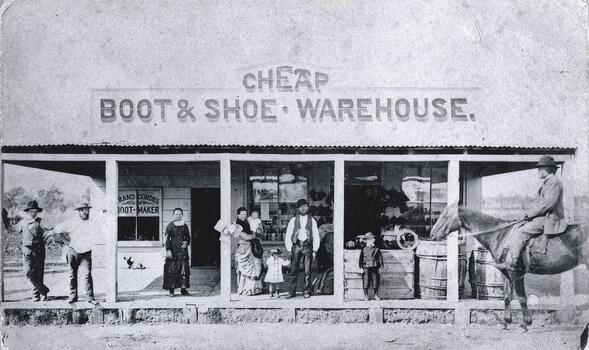 A group of people and a man on horseback at the front of Franz Gördes, Boot and Shoemaker store.