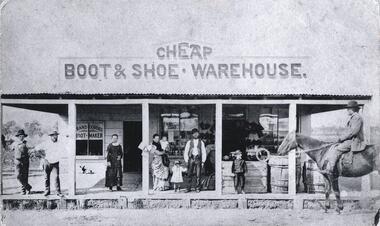 A group of people and a man on horseback at the front of Franz Gördes, Boot and Shoemaker store.