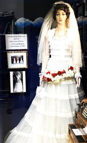 A wedding dress of lace with pale blue satin underskirt. Bouquet of red and cream roses