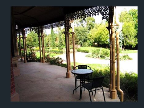 View from verandah towards gardens. Wrought iron work visible along roof line.