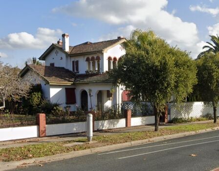 A large Italianate style teo storey home surrounded by garden and trees