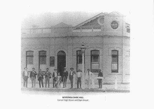 11 men standing outside a white stone building with Shire Offices in circle at the top
