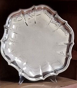 A circular silver tray with embossed pattern around edge.