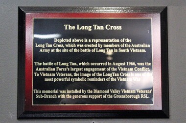 Rectangular plaque, dark timber with inside red border and golden text with a brief background of the Battle of Long Tan.