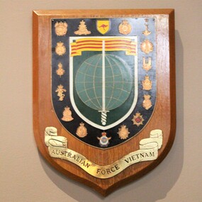 Wooden plaque with title scroll 'Australian Forces Vietnam' and depictions of 'pins' from the various elements of the Armed Forces.