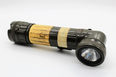 Army issued battery powered torch; olive drab in colour with beacon at right-angle to trunk.