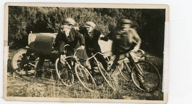 Photograph - Black and White Photograph, Four Cyclists and car in background