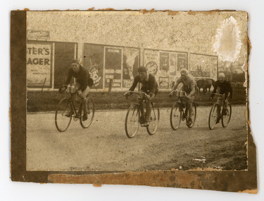 Photograph - Black and White Photograph, Four Cyclists riding past Billboards