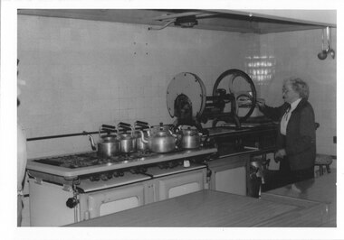 "Shrublands" mansion kitchen Miss Appleby,  matron of St. John's Home for Boys and Girls,  demonstrating the meat and cheese slicer