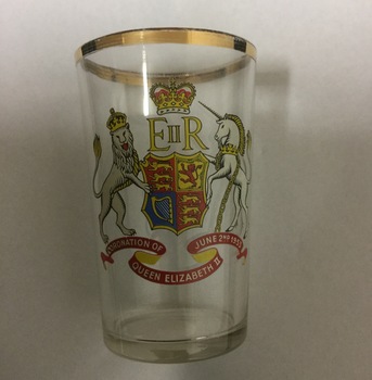 A clear drinking glass with a gold rim commemorating the coronation of Queen Elizabeth II.