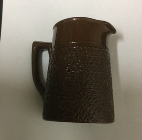 Brown China jug, with handle. Has 'stippled' pattern on bottom section.