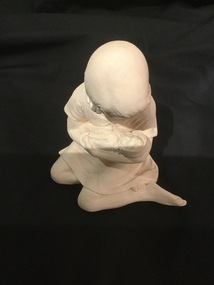 White coloured clay Pottery girl seated, nursing doll.