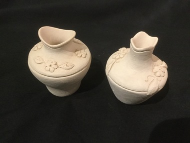 Two small white pottery vases with floral relief design.