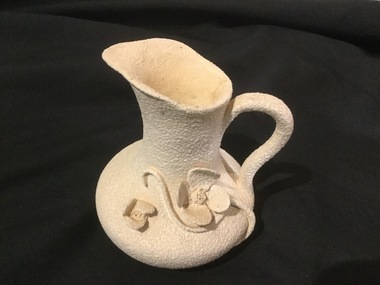 White Pottery jug with matt glaze, and decorative work on outside.