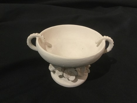White Pottery bowl with handles and flowers at base.