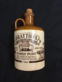 A brown and beige ceramic wine flagon, with a handle and cork stopper.