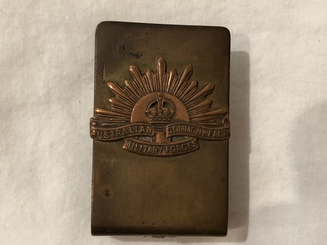 An open metal rectangular shaped matchbox cover with Rising Sun insignia Australian Commonwealth Military Forces in raised lettering.